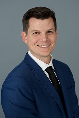 Frank Roessler wearing a dark blue colored jacket, white colored shirt and black tie